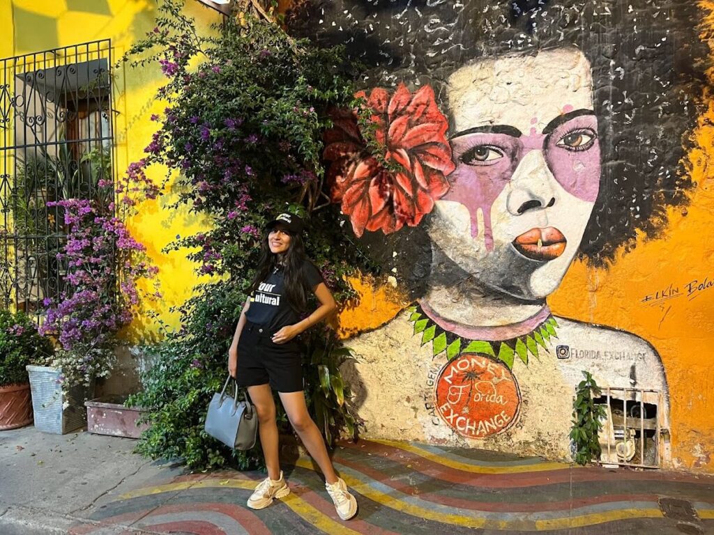 Roxeus posing in front of vibrant street art in Getsemaní, Cartagena, Colombia.