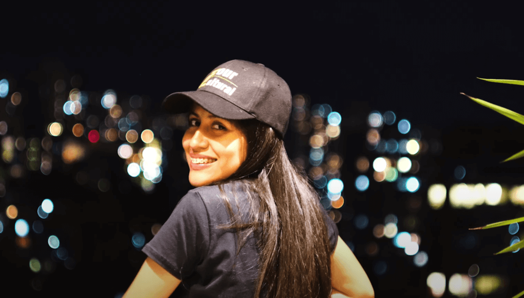 Roxeus smiling at night in Medellín with city lights in the background.