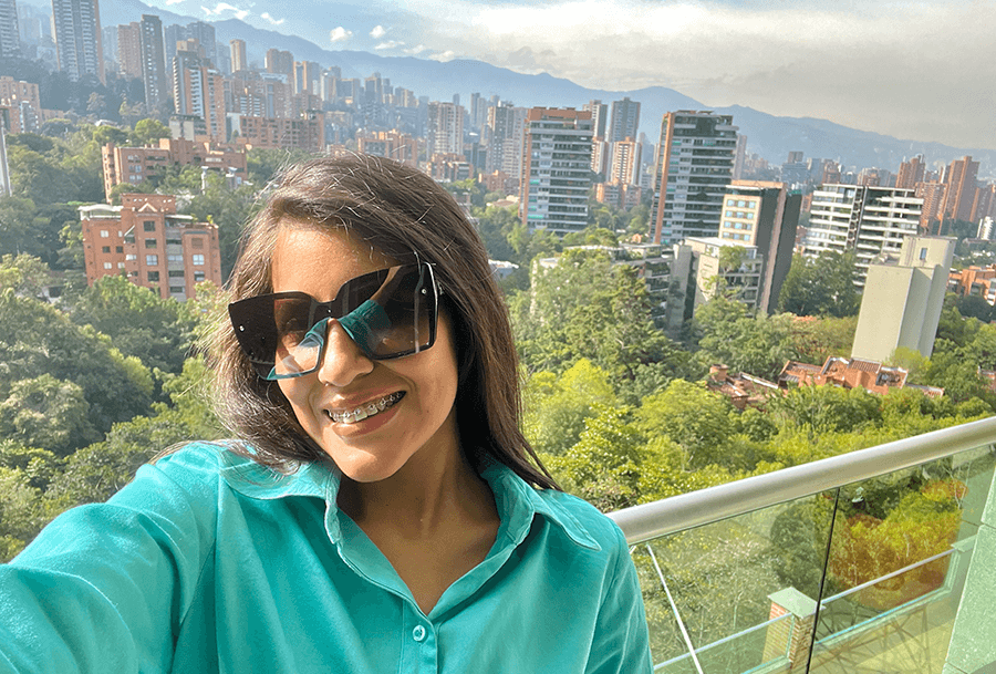 Roxeus taking a selfie with a panoramic view of El Poblado, Medellín, from an Airbnb balcony.